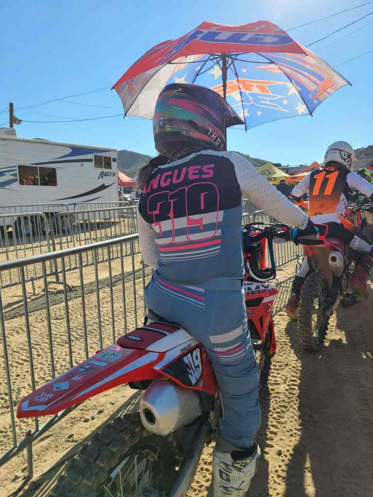 Motocross rider with umbrella at the starting line, ready for race.