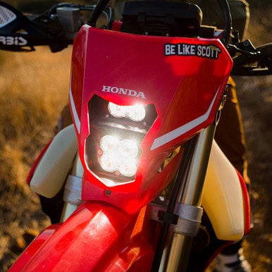 Honda dirt bike with LED headlight and "Be Like Scott" sticker on the front.