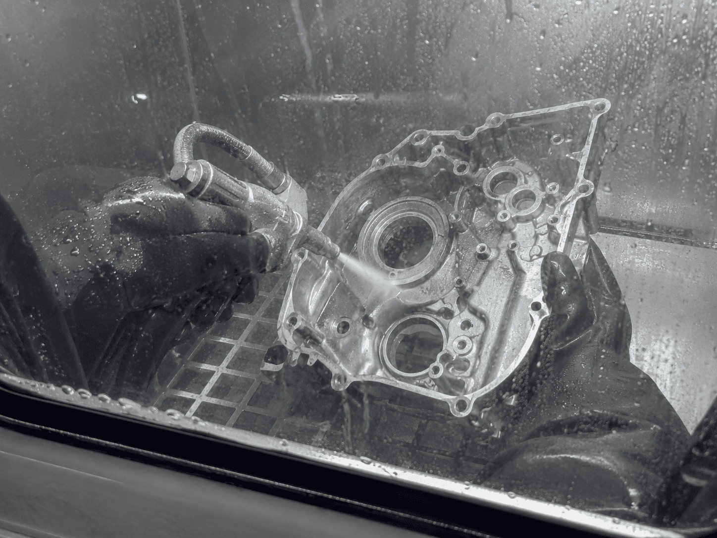 Dirt-bike engine component being vapor honed inside the cabinet